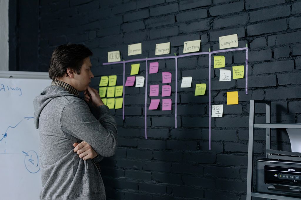 Adult male focusing on task planning using sticky notes on a black wall in a contemporary office setting.